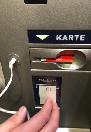 Geldautomat mit eindeutigem Kartenslot und den eingesteckten Kopfhörern